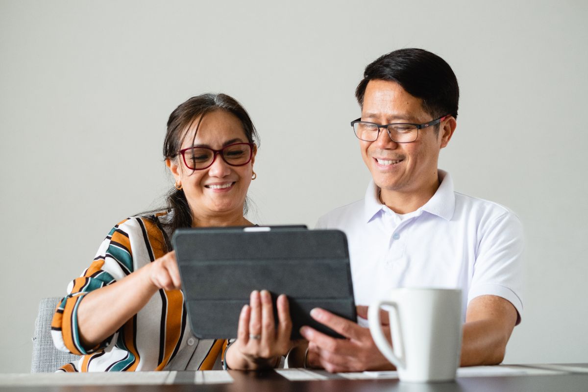 couple smile as they use a tablet